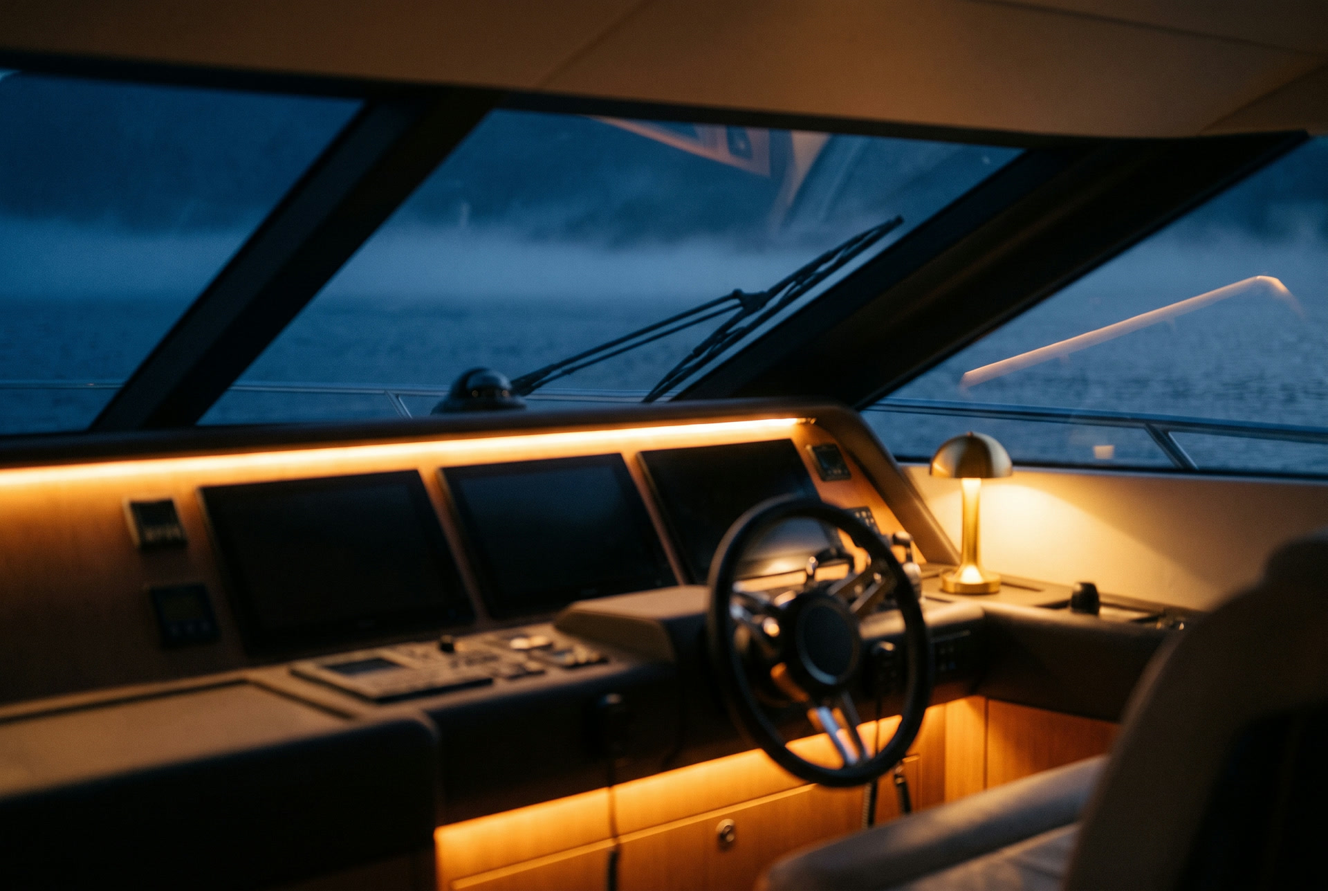A modern yacht helm station at night, warm amber accent lighting